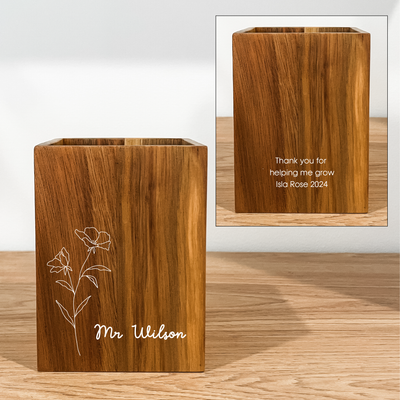 A wooden pencil holder with a floral design and a personalized engraving that reads 'Thank you for helping me grow - Mr Wilson'.