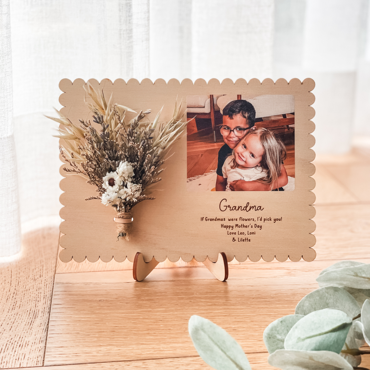 Decorative Mother's Day photo frame with a photo of two children and the word 'Grandma' on a wooden surface.